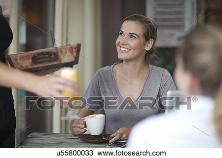 Two young adult female friends ordering from menu in cafe View Large Photo Image Stock Image - Two young adult female friends ordering from menu in cafe. Fotosearch