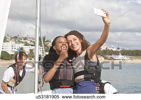 Two young female friends taking self portrait with sailboat View Large Photo Image Stock Photography - Two young female friends taking self portrait with sailboat. Fotosearch