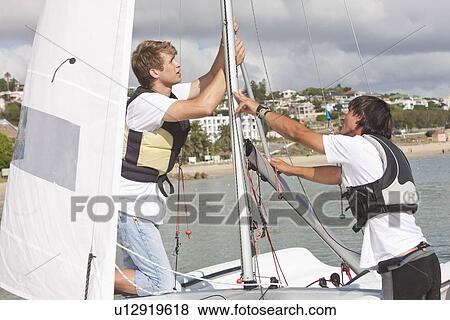 Two young men hauling up sail on boat View Large Photo Image Stock Photo - Two young men hauling up sail on boat. Fotosearch
