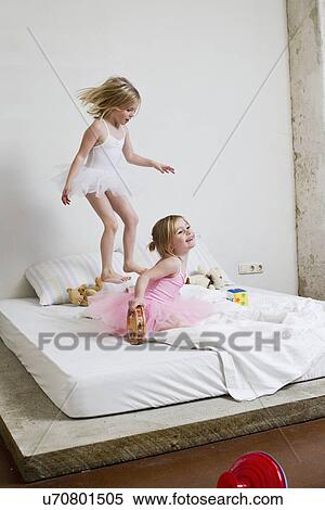 Stock Photography - Two young sisters dressed as ballet dancers playing on bed. Fotosearch