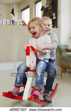 Two young sisters playing on rocking horse View Large Photo Image Stock Photo - Two young sisters playing on rocking horse. Fotosearch