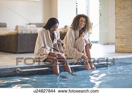 Picture - Two young women relaxing on edge of spa swimming pool. Fotosearch