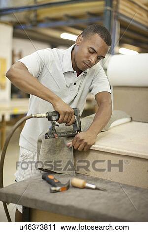 Upholsterer attaching textile to frame using staple gun View Large Photo Image Stock Image - Upholsterer attaching textile to frame using staple gun. Fotosearch