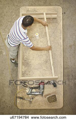 Upholsterer constructing a wooden frame on table View Large Photo Image Picture - Upholsterer constructing a wooden frame on table. Fotosearch