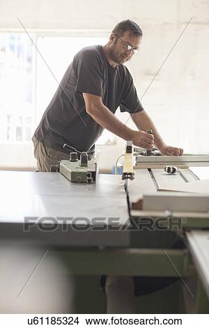 Picture - Upholsterer preparing planks on miter saw. Fotosearch