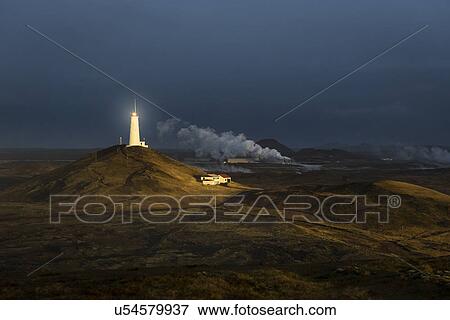 Stock Photo - View of distant glowing lighthouse, Reykjanes, Iceland. Fotosearch
