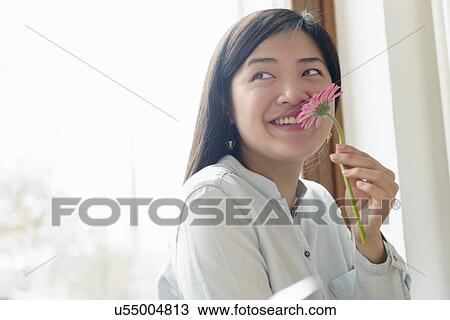 Stock Image - Woman smelling flower. Fotosearch