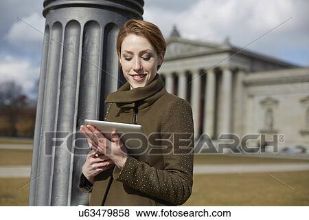 Woman using digital tablet, monument in background, Munich, Germany View Large Photo Image Stock Photo - Woman using digital tablet, monument in background, Munich, Germany. Fotosearch