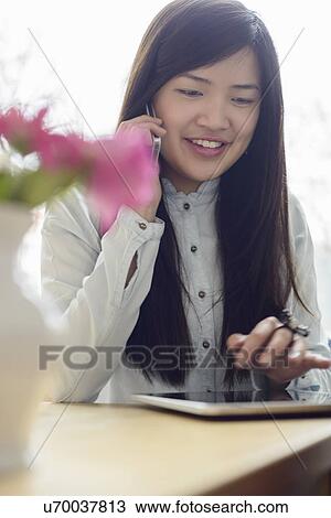 Stock Image - Woman using phone and digital tablet. Fotosearch