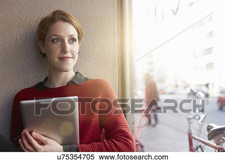 Stock Photography - Woman with digital tablet by window. Fotosearch