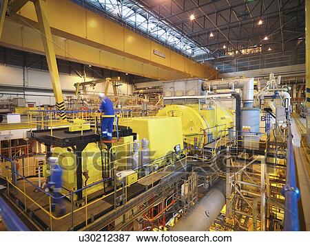 Stock Photo - Workers in turbine hall of power station. Fotosearch