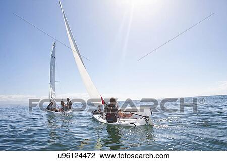 Young adult friends racing each other in sailboats View Large Photo Image Stock Image - Young adult friends racing each other in sailboats. Fotosearch
