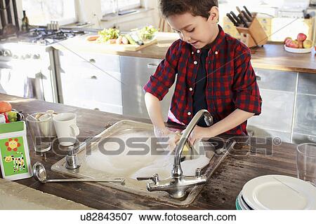 Young boy washing up in kitchen View Large Photo Image Stock Photo - Young boy washing up in kitchen. Fotosearch