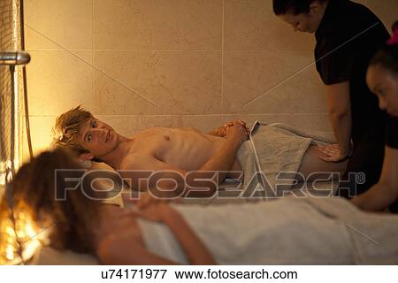 Young couple chatting whilst having a massage in spa View Large Photo Image Stock Photo - Young couple chatting whilst having a massage in spa. Fotosearch