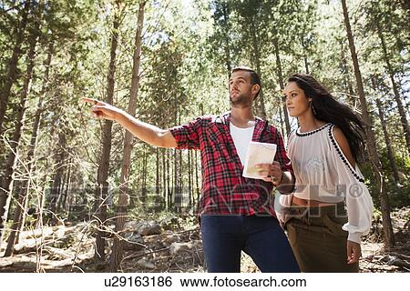 Stock Photograph - Young couple in forest, man pointing. Fotosearch
