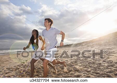Picture - Young couple running on beach. Fotosearch