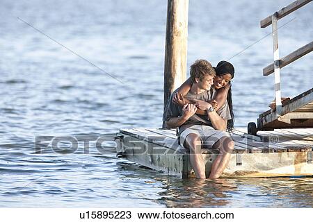 Young couple sitting on jetty View Large Photo Image Stock Image - Young couple sitting on jetty. Fotosearch
