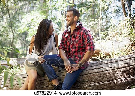 Young couple sitting on tree in forest View Large Photo Image Picture - Young couple sitting on tree in forest. Fotosearch