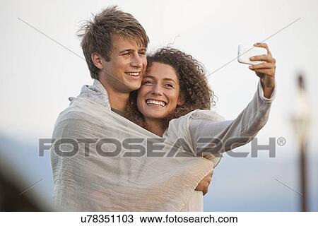 Stock Image - Young couple taking picture of themselves. Fotosearch