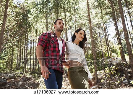 Young couple walking through forest, arm around View Large Photo Image Stock Photo - Young couple walking through forest, arm around. Fotosearch