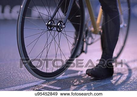 Stock Photo - Young female cyclist waiting at start line on velodrome track. Fotosearch