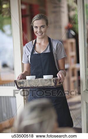 Young female waitress carrying tray of coffee cups in cafe View Large Photo Image Stock Photo - Young female waitress carrying tray of coffee cups in cafe. Fotosearch