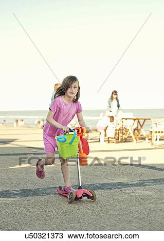 Young girl with bucket and spade on push scooter, Southwold, Sussex, UK View Large Photo Image Stock Image - Young girl with bucket and spade on push scooter, Southwold, Sussex, UK. Fotosearch