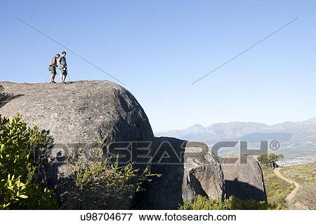 Stock Photo - Young male climbers attaching ropes and harnesses on rock. Fotosearch