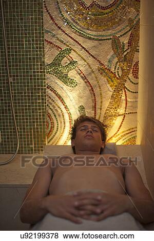 Young man lying on back and relaxing in spa sauna View Large Photo Image Stock Photo - Young man lying on back and relaxing in spa sauna. Fotosearch