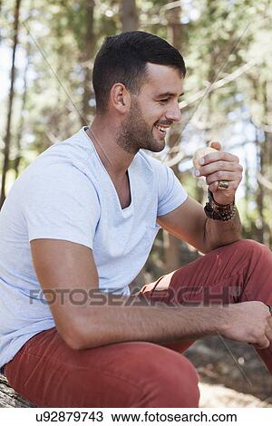 Stock Image - Young man sitting in forest. Fotosearch