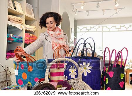 Young woman browsing shopping bags in boutique View Large Photo Image Stock Photo - Young woman browsing shopping bags in boutique. Fotosearch