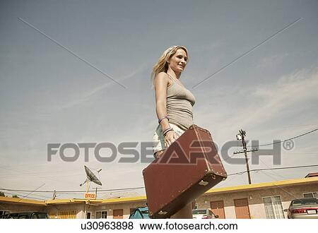 Young woman carrying suitcase to motel View Large Photo Image Stock Photo - Young woman carrying suitcase to motel. Fotosearch