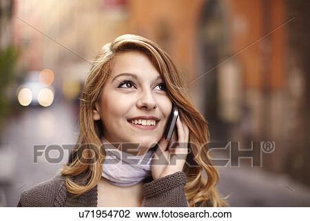 Stock Image - Young woman chatting on smartphone on Rome street, Italy. Fotosearch