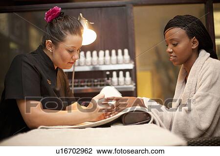 Stock Image - Young woman having nail manicure in spa. Fotosearch