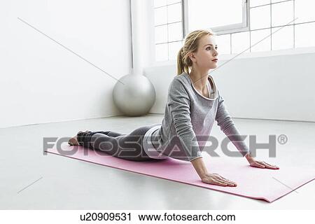Stock Image - Young woman in yoga pose on yoga mat. Fotosearch