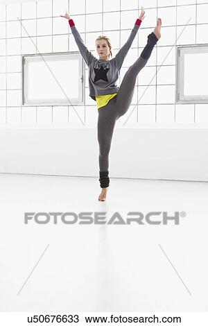 Stock Image - Young woman jumping in gymnasium. Fotosearch