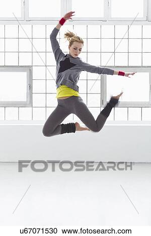 Young woman jumping in gymnasium View Large Photo Image Stock Image - Young woman jumping in gymnasium. Fotosearch