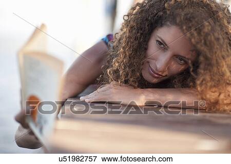 Young woman laying on jetty, reading book View Large Photo Image Stock Photo - Young woman laying on jetty, reading book. Fotosearch