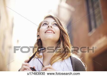 Stock Image - Young woman looking up at buildings, Rome, Italy. Fotosearch