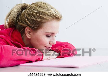 Young woman lying on exercise mat View Large Photo Image Stock Image - Young woman lying on exercise mat. Fotosearch