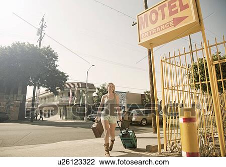 Young woman pulling wheeled suitcase to motel View Large Photo Image Stock Image - Young woman pulling wheeled suitcase to motel. Fotosearch