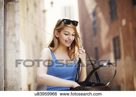 Young woman searching in shoulder bag, Rome, Italy View Large Photo Image Stock Photograph - Young woman searching in shoulder bag, Rome, Italy. Fotosearch