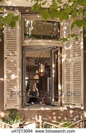 Young woman serving coffee to customer, viewed through coffee shop window View Large Photo Image Picture - Young woman serving coffee to customer, viewed through coffee shop window. Fotosearch