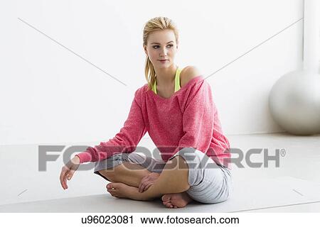 Young woman sitting on exercise mat View Large Photo Image Stock Image - Young woman sitting on exercise mat. Fotosearch