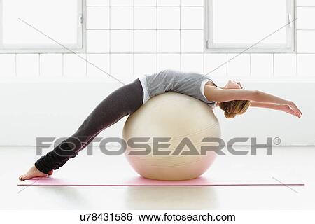 Young woman stretching on exercise ball View Large Photo Image Stock Photograph - Young woman stretching on exercise ball. Fotosearch