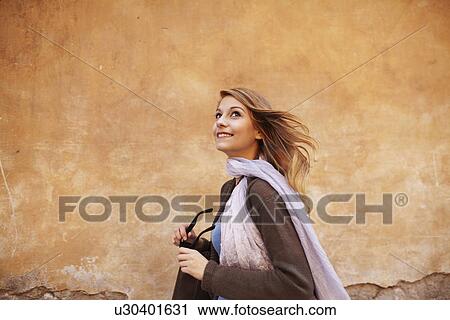 Stock Image - Young woman strolling down street looking sideways. Fotosearch