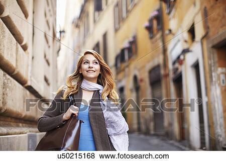 Stock Photo - Young woman strolling down street, Rome, Italy. Fotosearch
