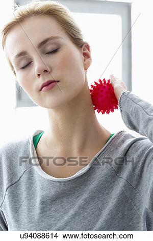Picture - Young woman using massage ball on neck. Fotosearch