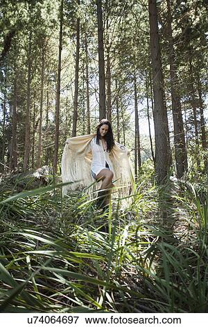 Stock Photo - Young woman walking through forest. Fotosearch