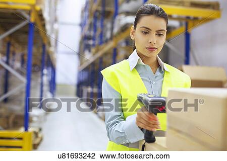 Stock Image - Young woman with barcode reader in distribution warehouse. Fotosearch